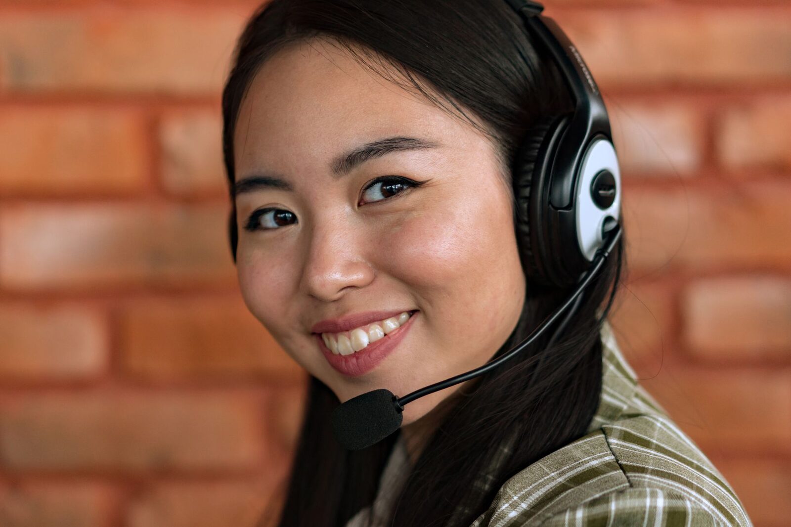 Close-up of a young Asian woman wearing headphones and smiling, indoors.